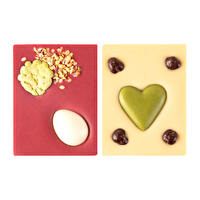 Mi-Xing Ostermini im 2er-Pack von Zotter sind zwei kleine Osterüberraschungen in einem. Eine kleine vegane Tafel aus Sojaschokolade mit einer Walnussnougatfüllung mit Duftrosen und Grüntee- sowie Kokoseiern dekoriert. Die zweite Tafel besteht aus Kokoskuvertüre, zwei Himbeerherzen und weißen Reisflakes.
